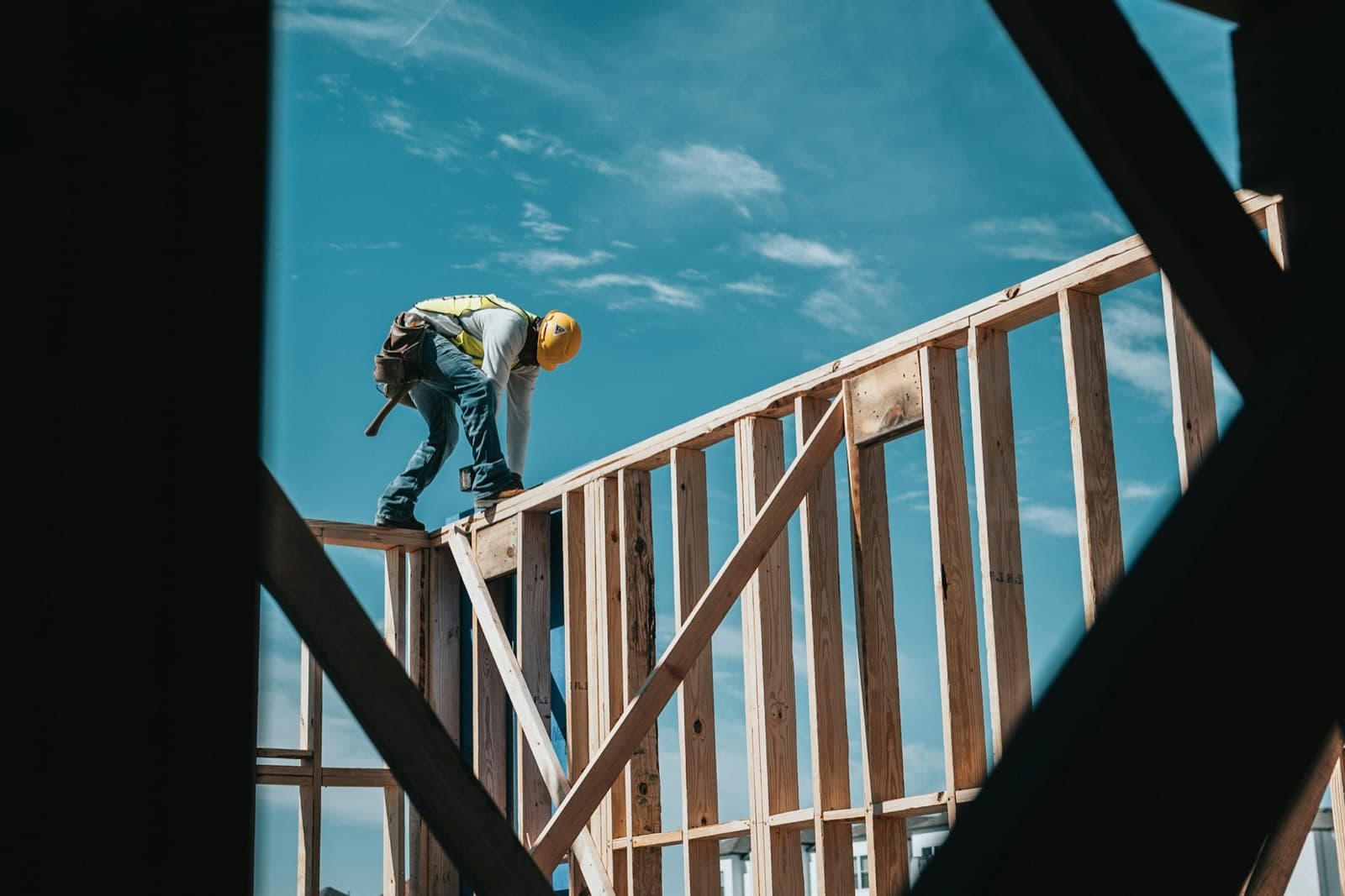 A framer in a hard hat working on top of a new home's wall framing