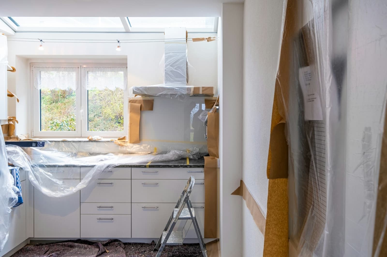 A kitchen mid-renovation, with counters and the range hood wrapped in protective plastic